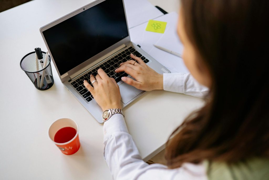 Adult woman working on a laptop in a modern office environment, focusing on productivity.